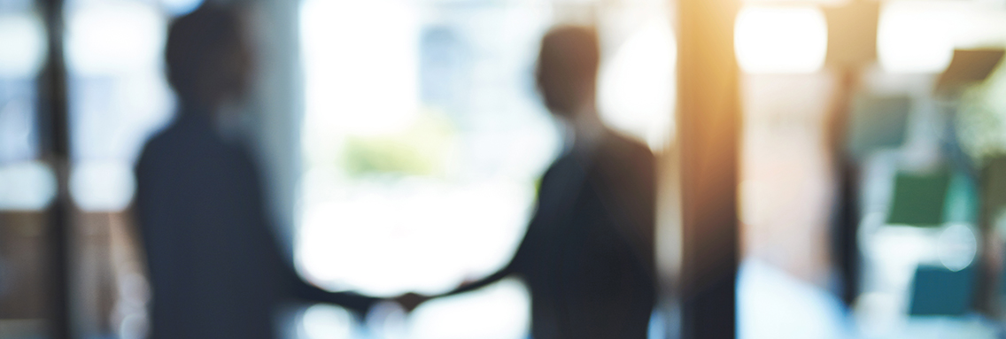 Defocused shot of two businesspeople shaking hands in an office